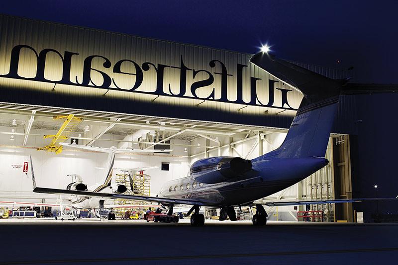 Exterior of Gulf Stream Service Center at night. Plane entering hangar.